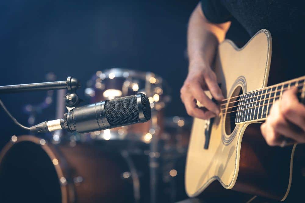 person playing an acoustic guitar in front of a microphone