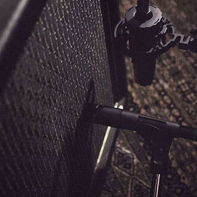 Image of a microphone placed next to a guitar amplifier.