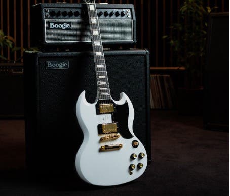 White Epiphone SG guitar resting upright on an amp